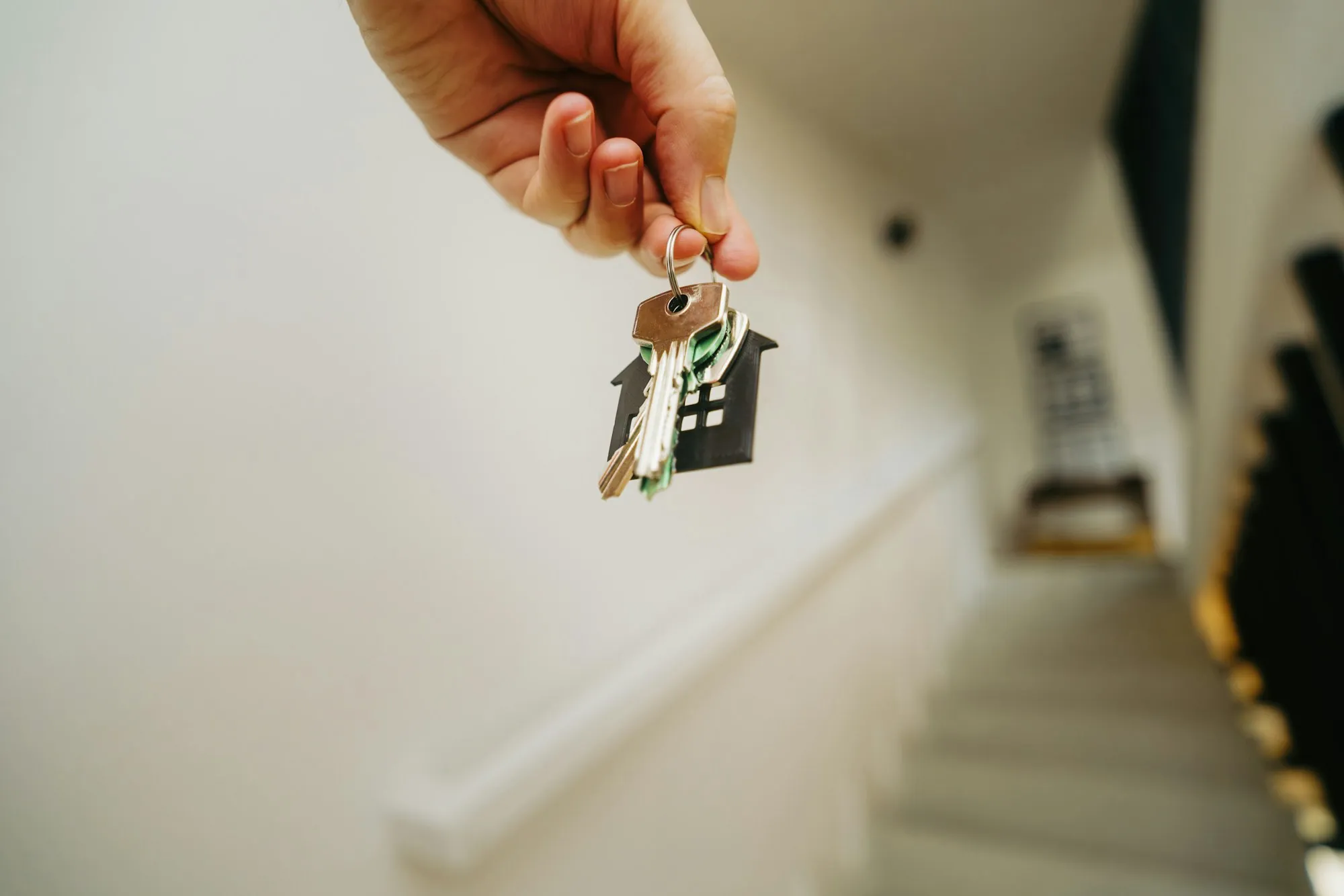 Hand holding up keys with a house-shaped key chain