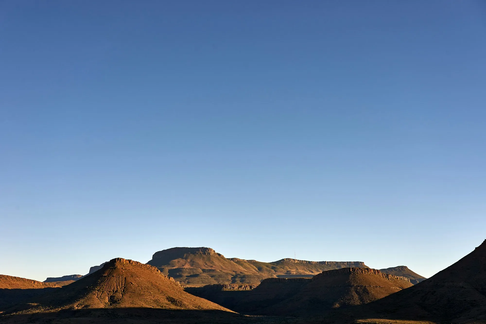 Desert buttes silhouetted under a clear sky