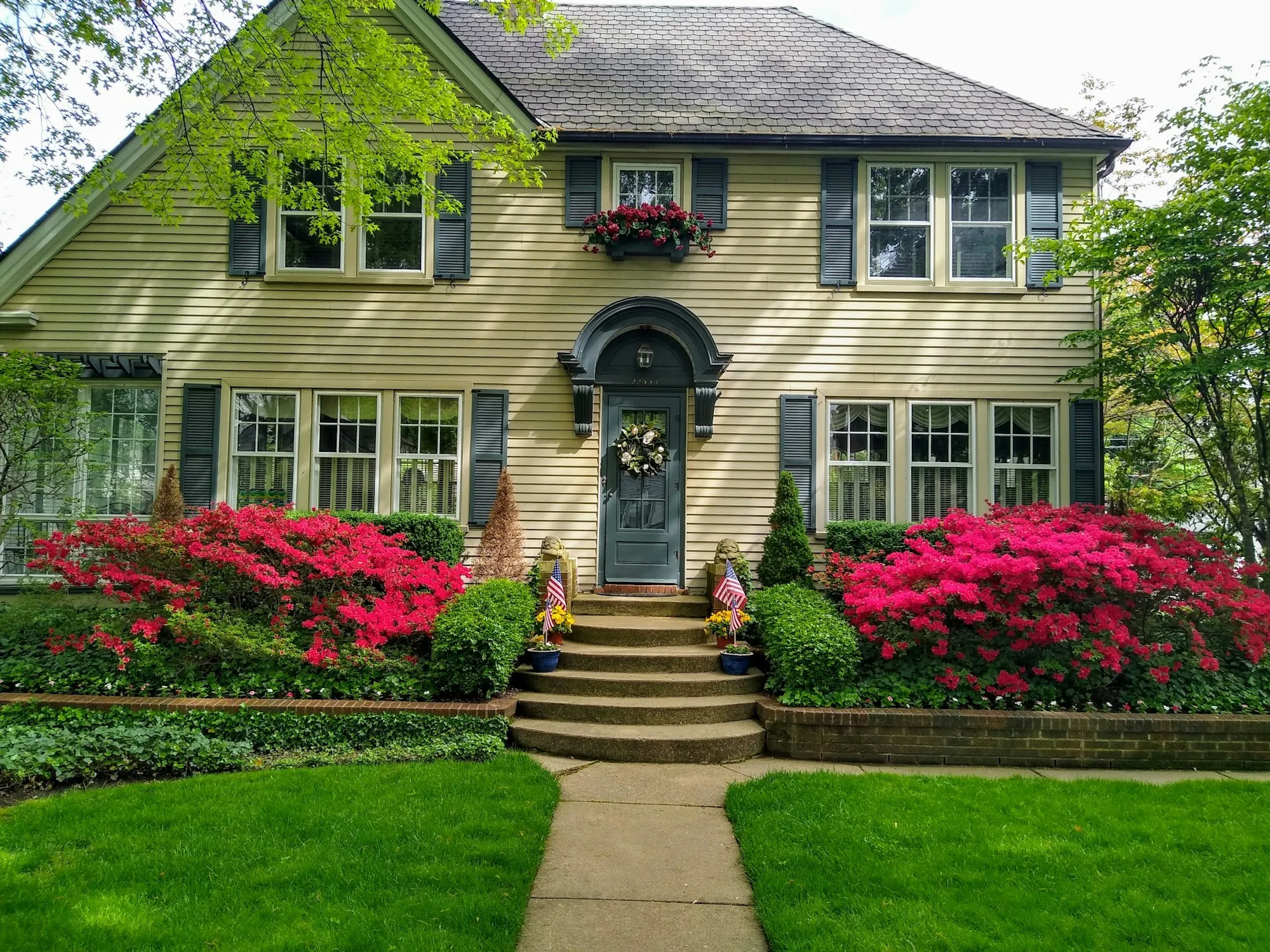 Colonial-style house with pink azaleas along the front steps, illustrating the cost to sell a house in Shafter, California