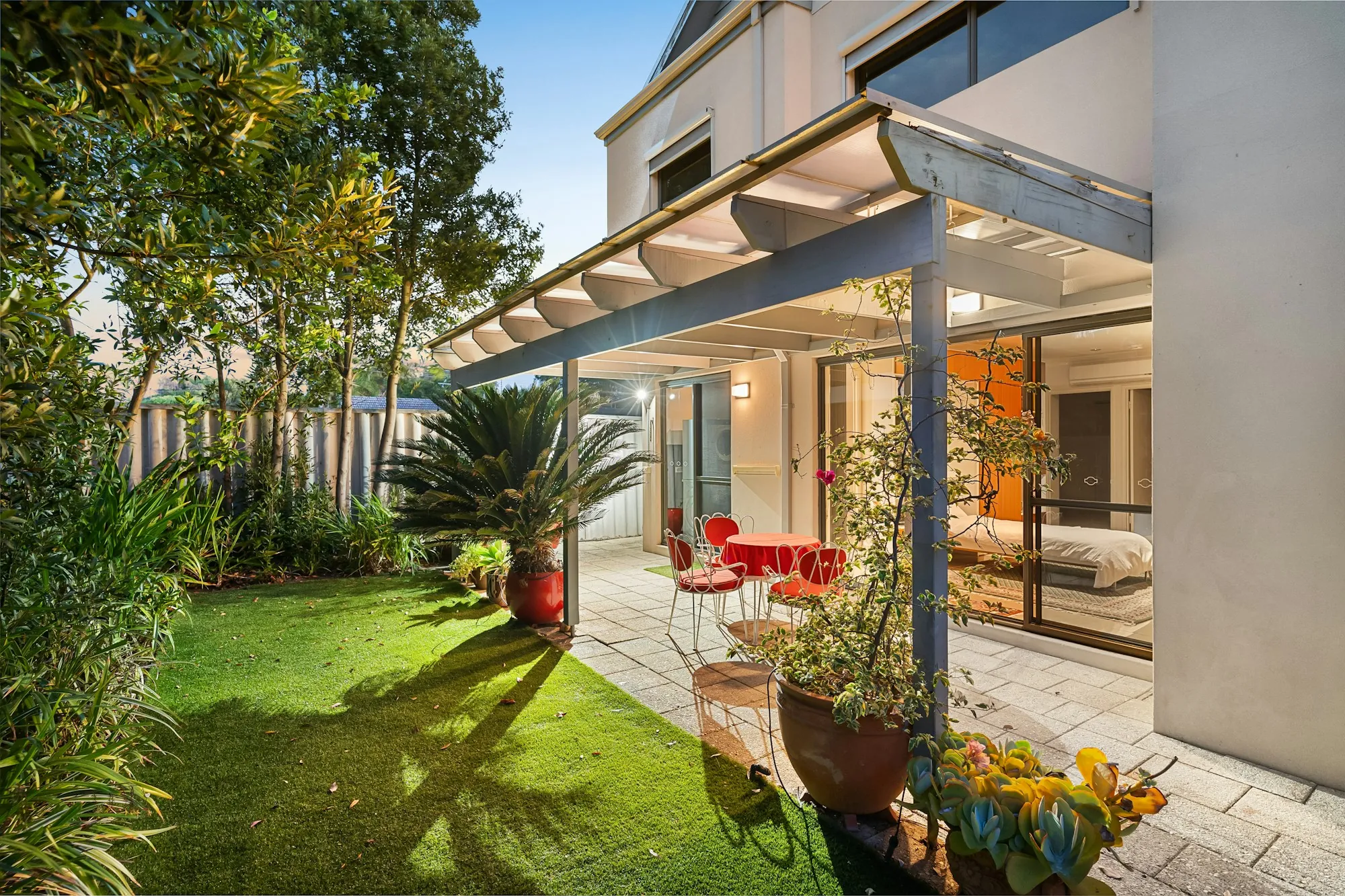 Covered patio beside a lawn and potted plants at a modern home